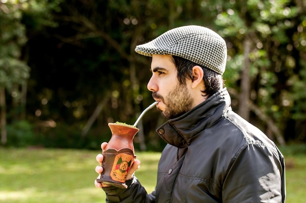 Uomo gaucho con barba e berretto che beve il tè del compagno in una giornata di sole