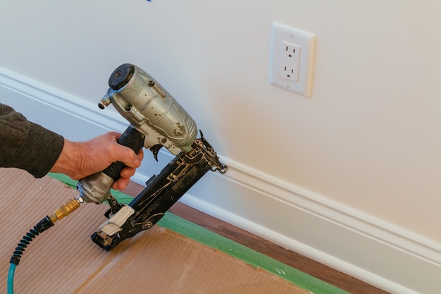 Gauge finish nailer uomo inchiodato doghe appaltatore casa su una sezione di muro per il lusso