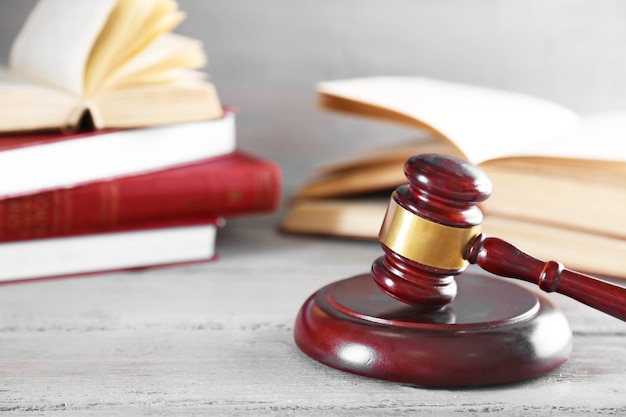 Gavel and books on wooden table on grey background