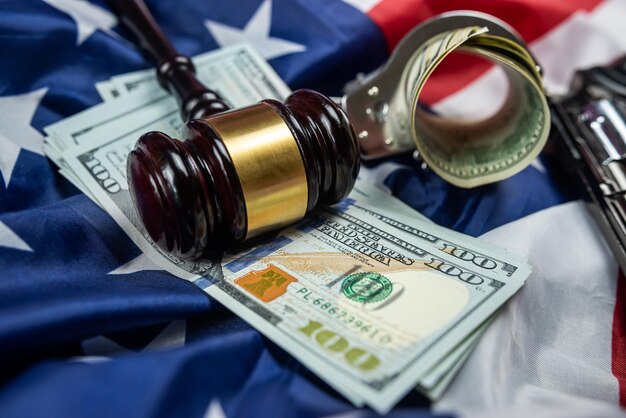 Gavel and handcuffs and money dollars and a gun on the background of the American flag of the USA judiciary law crime and punishment criminal justice