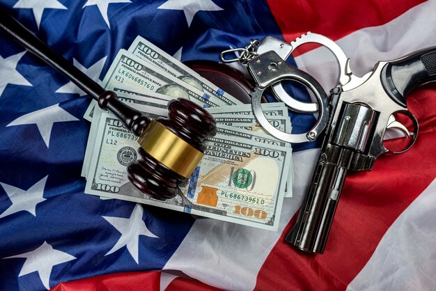 Gavel and handcuffs and money and gun on the background of the American flag of the USA judiciary law crime and punishment