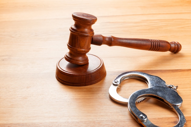 Gavel and handcuffs on wooden table