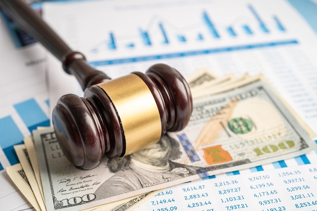 Photo gavel for judge lawyer with us dollar banknotes on chart graph paper finance concept