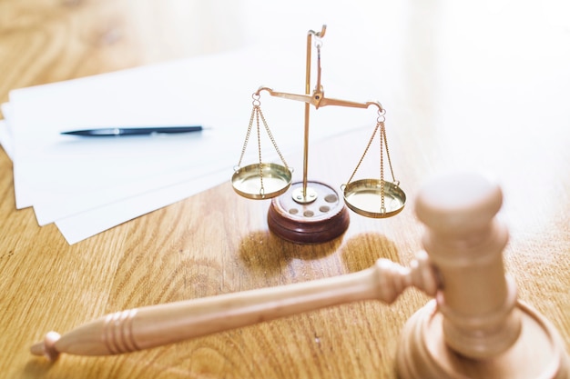 Photo gavel; justice scale; pen and blank papers on wooden desk