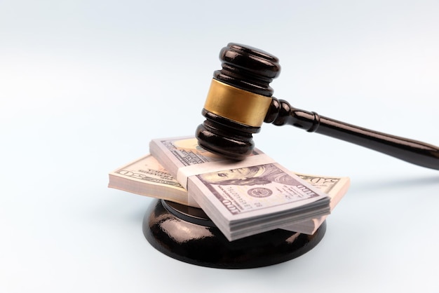 Gavel on top of pile of money on blue background