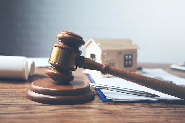 Gavel with house model and coins on table