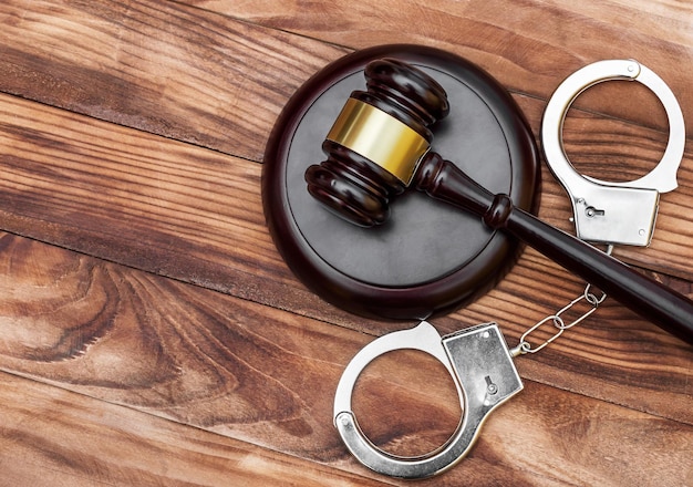 Gavel with stand and handcuffs on the wooden background Top view