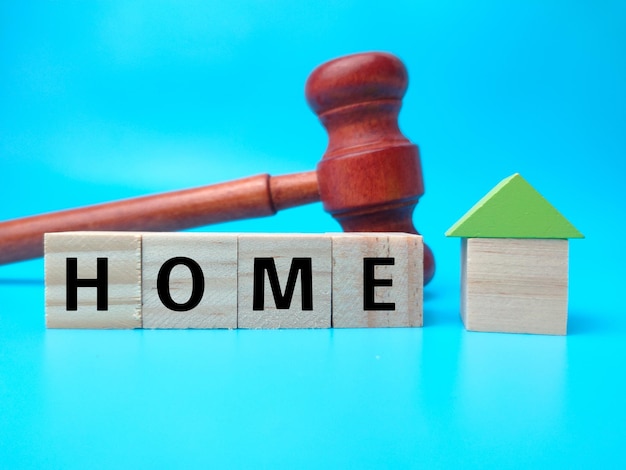 Gavel and wooden cube with word HOME on blue background