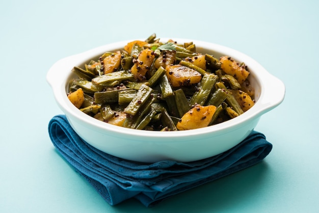 Gawar ki sabzi - Cluster Beans Curry with potato and spices served in a bowl over moody background. Selective focus