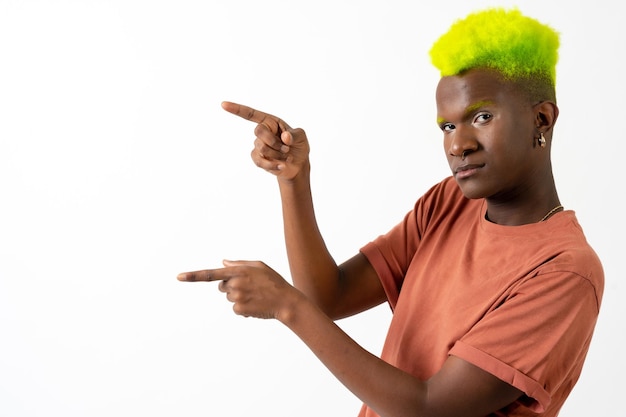 A gay black man in studio against a white background lgtbi\
concept pointing to the left