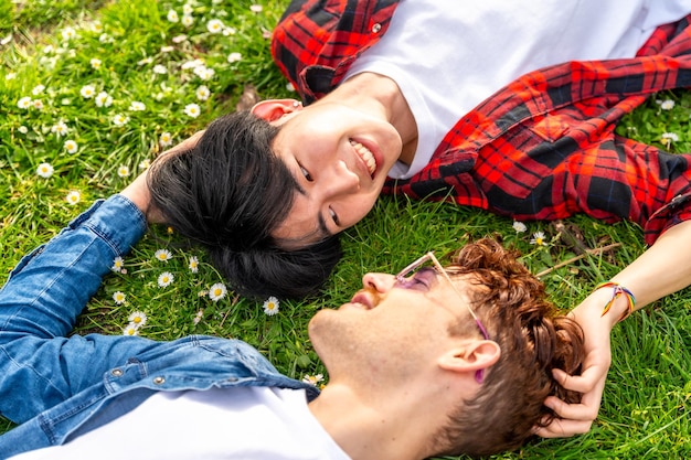 Влюбленная гомосексуальная пара лежит на траве и смотрит друг на друга.