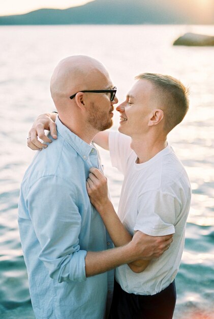 Гомосексуальная пара обнимается и почти целуется в море.