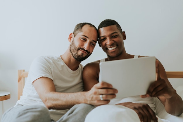 Photo gay couple using a tablet in bed