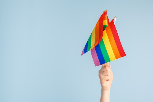 Gay flags in women's hand on grey background