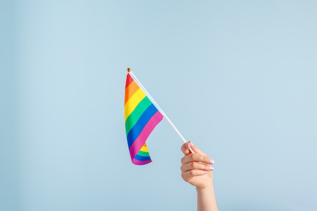 Gay flags in women's hand on grey