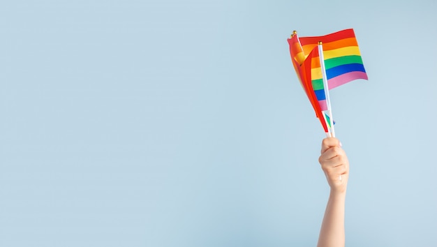 Gay flags in women's hand on grey 