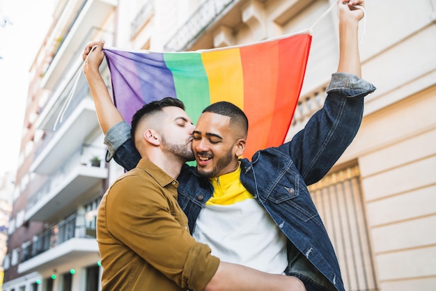 Foto gay koppel met regenboogvlag terwijl ze in de stad staan