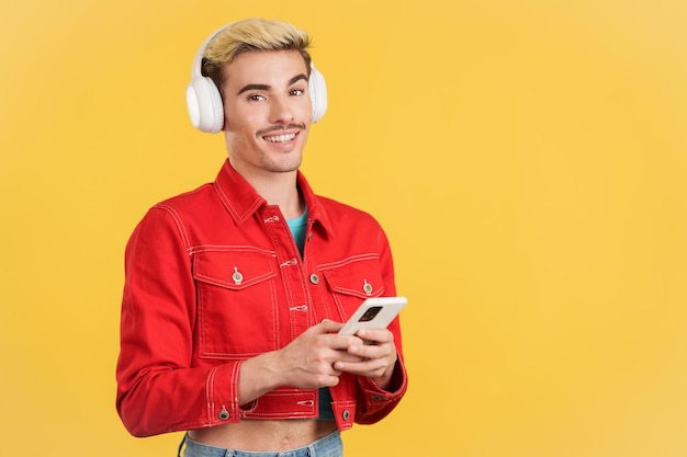 Photo gay man looking at camera listening to music with mobile