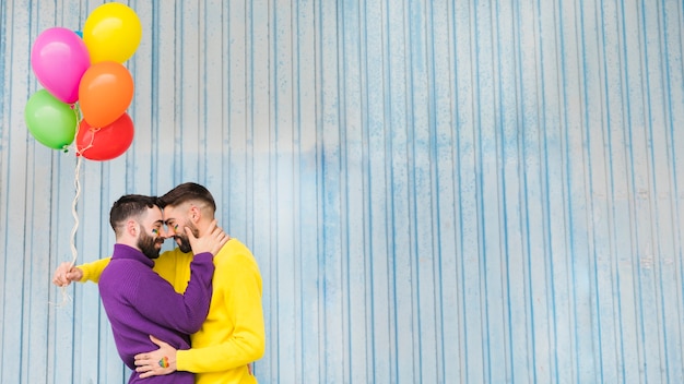 Gay men hugging and holding colorful balloons