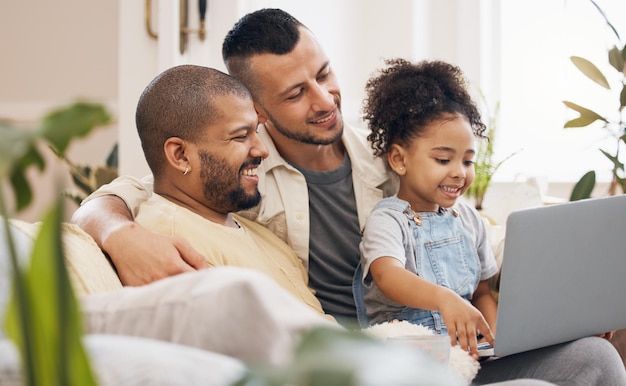 Gay ouders en meisje met een laptop thuis en verbinding met liefde streaming films en binding in een woonkamer Mensen familie of vaders met vrouwelijk kind kind en pc voor cartoon of film in een lounge