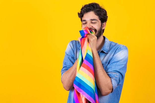 Gay pride ragazzo omosessuale che bacia la bandiera lgbt su sfondo giallo