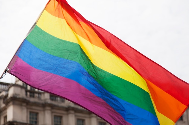 Gay rainbow flag being waved at an LGBT gay pride march in London