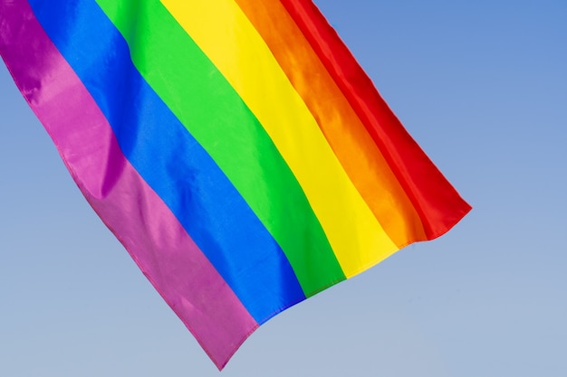 Gay rainbow flag waving in the wind in a clear blue sky