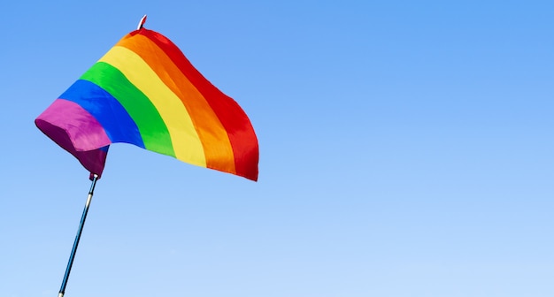 Gay regenboogvlag wappert in de wind in een heldere blauwe hemel