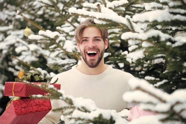 Photo gay smiling with presents on winter day season greetings and xmas gifts man holding red boxes in sno...