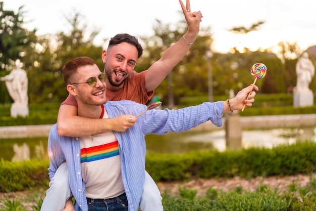 Gay vriendjes spelen en een klom op de rug terwijl ze een lolly aten in het park bij zonsondergang in het stad lgbt-concept