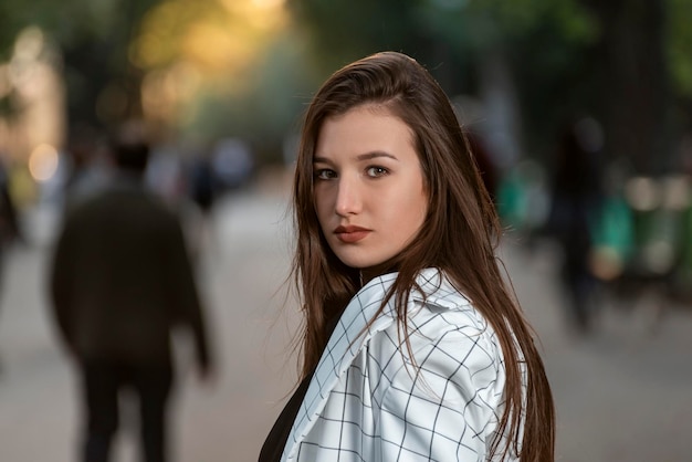 Gaze mischievous of ravenhaired young woman Portrait of attractive girl with long hair on park background