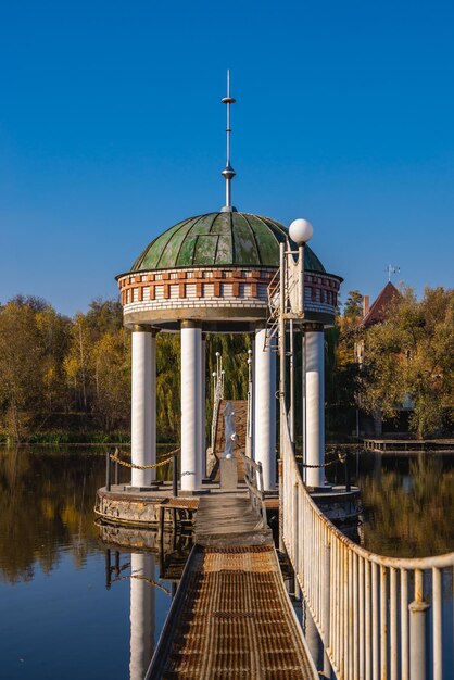 Photo gazebo in the middle of the lake on a sunny autumn evening in the village of ivanki ukraine