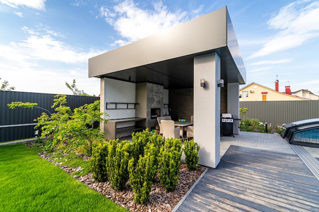 Gazebo with built-in barbecue. Table and chairs. Great design. Green lawn around