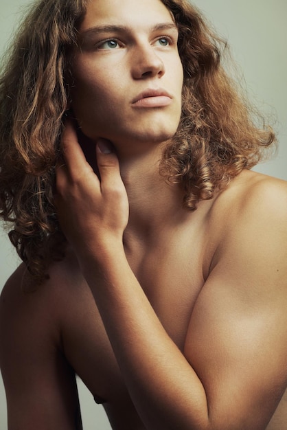 写真 遠くを見つめる長いブロンドの髪を持つハンサムな若い上半身裸の男