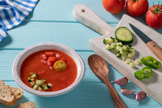 Il gazpacho andaluz è una zuppa fredda di pomodoro andalusa proveniente dalla spagna con cetriolo, aglio e pepe sul tavolo azzurro