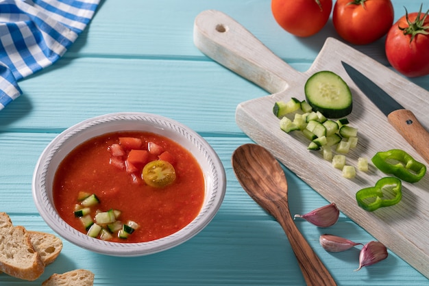 Gazpacho Andaluz is een Andalusische koude tomatensoep uit Spanje met komkommer, knoflook, peper op lichtblauwe tafel