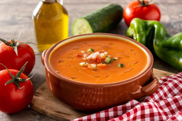 Gazpacho soup in crock pot and ingredient on wooden table