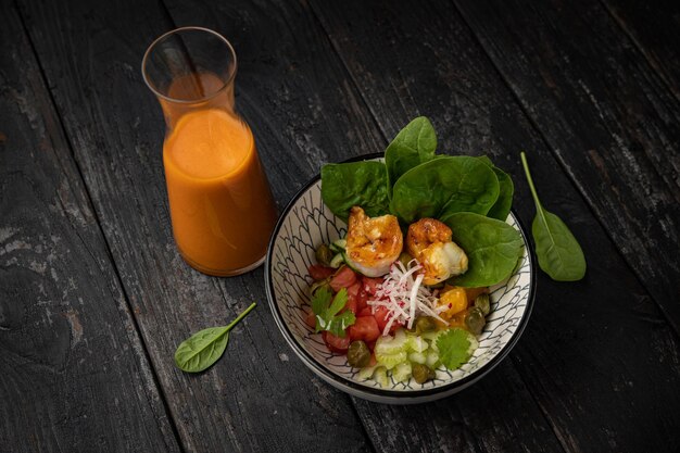 Gazpacho with spinach and vegetables on a wooden table