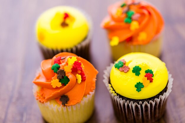 Geassorteerde cupcakes met geel en oranje glazuur gedecoreerd voor de herfst.