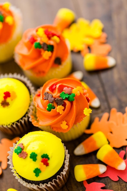 Geassorteerde cupcakes met geel en oranje glazuur gedecoreerd voor de herfst.