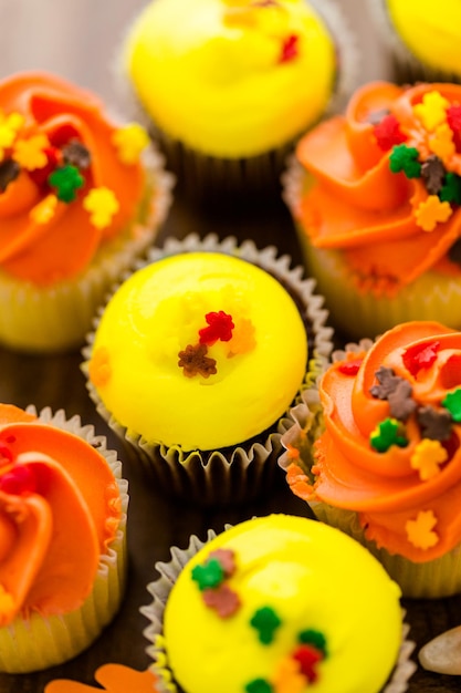 Geassorteerde cupcakes met geel en oranje glazuur gedecoreerd voor de herfst.