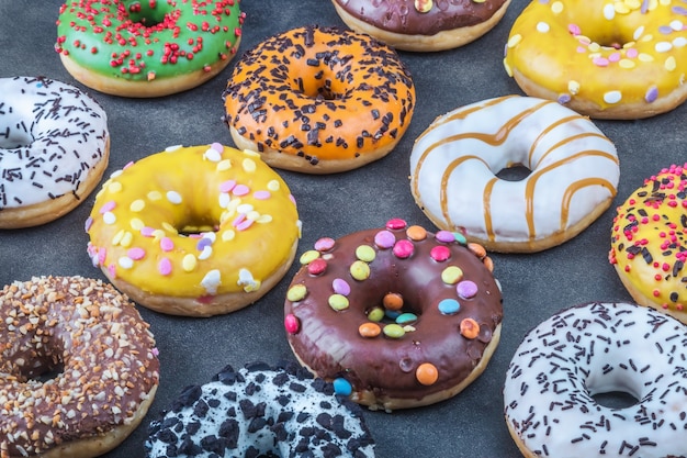 Geassorteerde donuts met suikerglazuur en gevoelens op een zwarte achtergrond. Achtergrond van diverse donuts met verschillende smaken