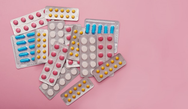 Geassorteerde farmaceutische geneeskundepillen, tabletten en capsules op roze achtergrond. Geneeskundeconcept en gezondheid