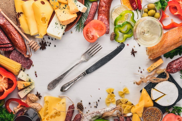 Geassorteerde kazen en traditionele worsten en groenten op een witte houten achtergrond Kaas brie blauwe kaas gorgonzola fuete salami Italiaanse traditionele keuken Vrije ruimte voor tekst Bovenaanzicht