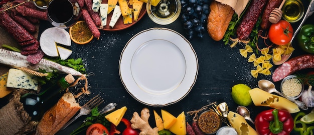 Foto geassorteerde kazen worsten wijnen traditionele kruiden en verse groenten op een houten ondergrond kaas brie blauwe kaas gorgonzola fuete salami italiaanse en spaanse keuken vrije ruimte