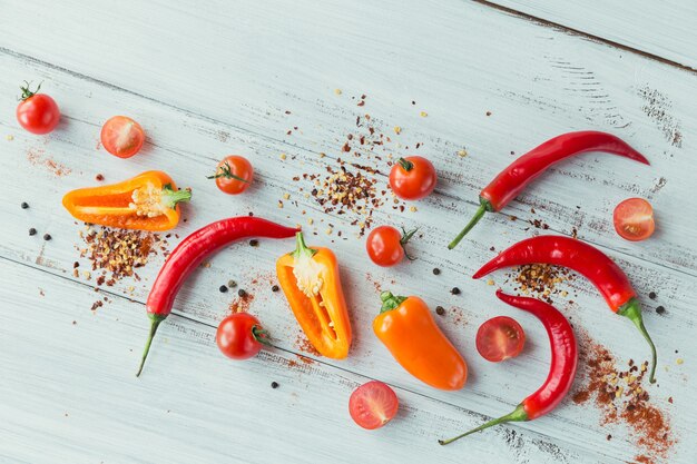 Geassorteerde paprika's, kerstomaatjes en kruiden op lichte houten tafel