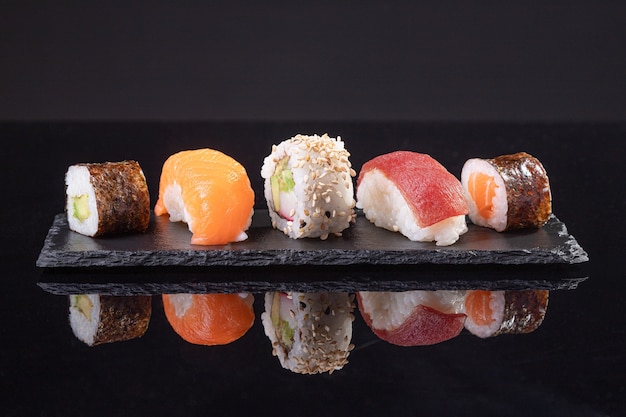 Foto geassorteerde sushi geserveerd op leisteen plaat op donkere achtergrond. japans eten.