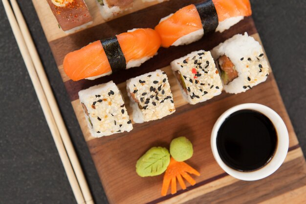 Geassorteerde sushi set geserveerd met stokjes en sojasaus op een houten bord