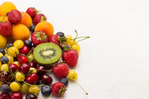 Geassorteerde verse bessen en fruit. Abrikozen Kiwi Aardbei Cherry Blueberry op witte achtergrond. Gewichtsverlies concept Bovenaanzicht. Kopieer ruimte.