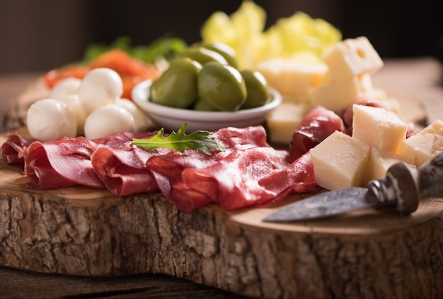 Geassorteerde vleeswaren en een bord kaas, op een houten snijplank. Italiaanse antipasti